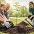 People of different ages planting a young tree in a park during Earth Day, with soil and a watering can nearby.